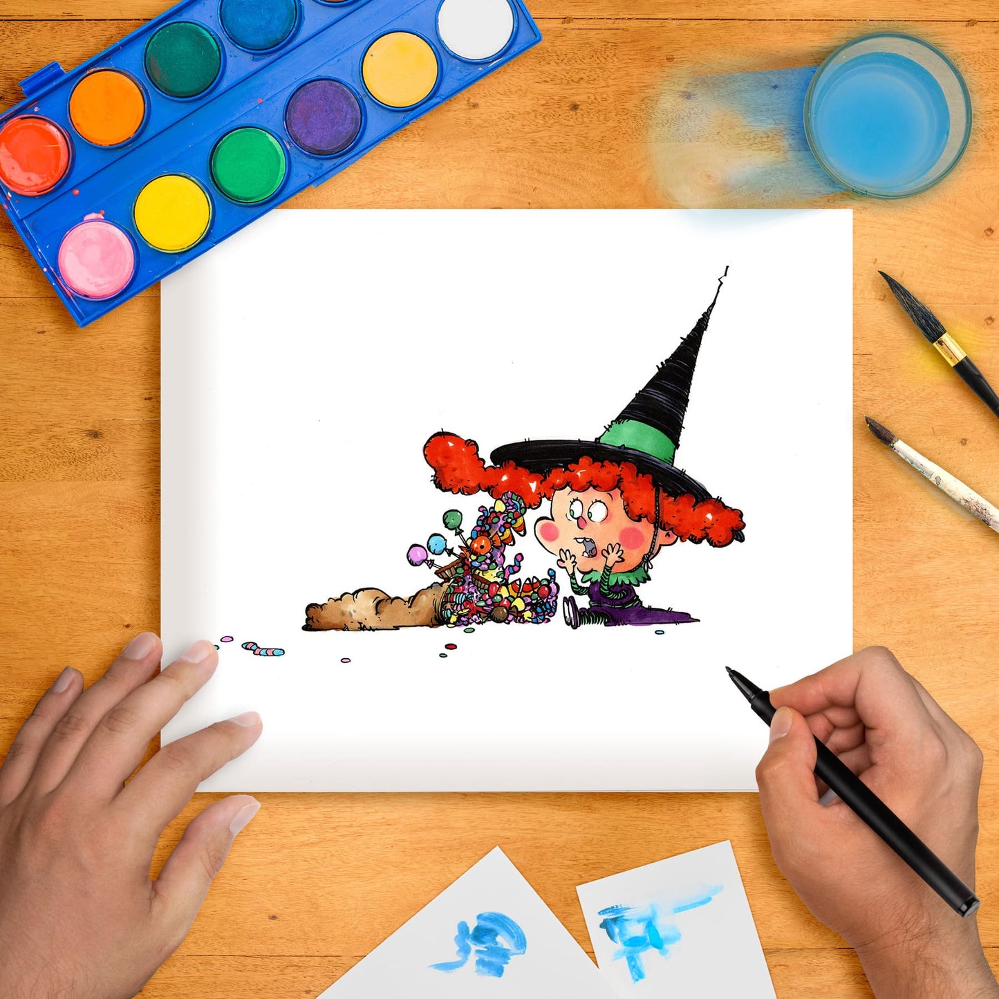 Original marker illustration of a whimsical character resembling a witch with candy, placed on a table with art supplies.