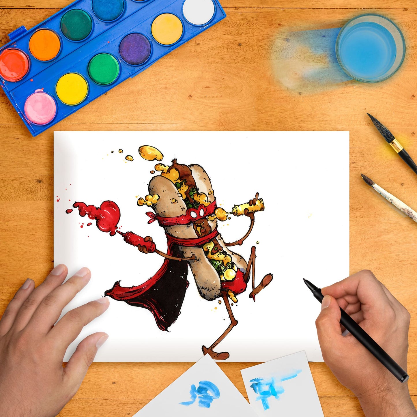 Original marker illustration artwork on paper depicting a cartoon-style hotdog character with condiments, placed on a table with art supplies around.