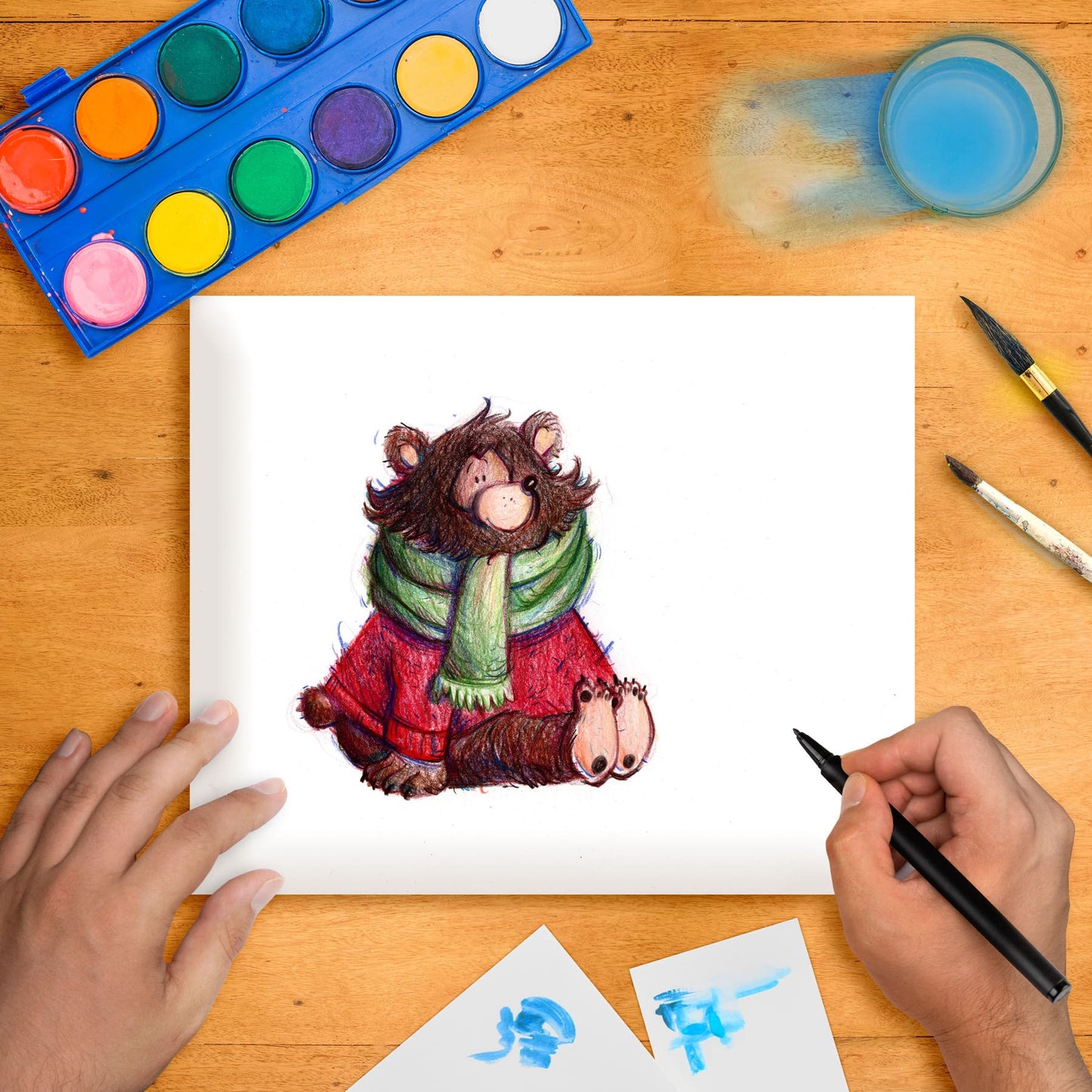 Original marker illustration of a bear wearing a coat and scarf, placed on a table with art supplies around it.