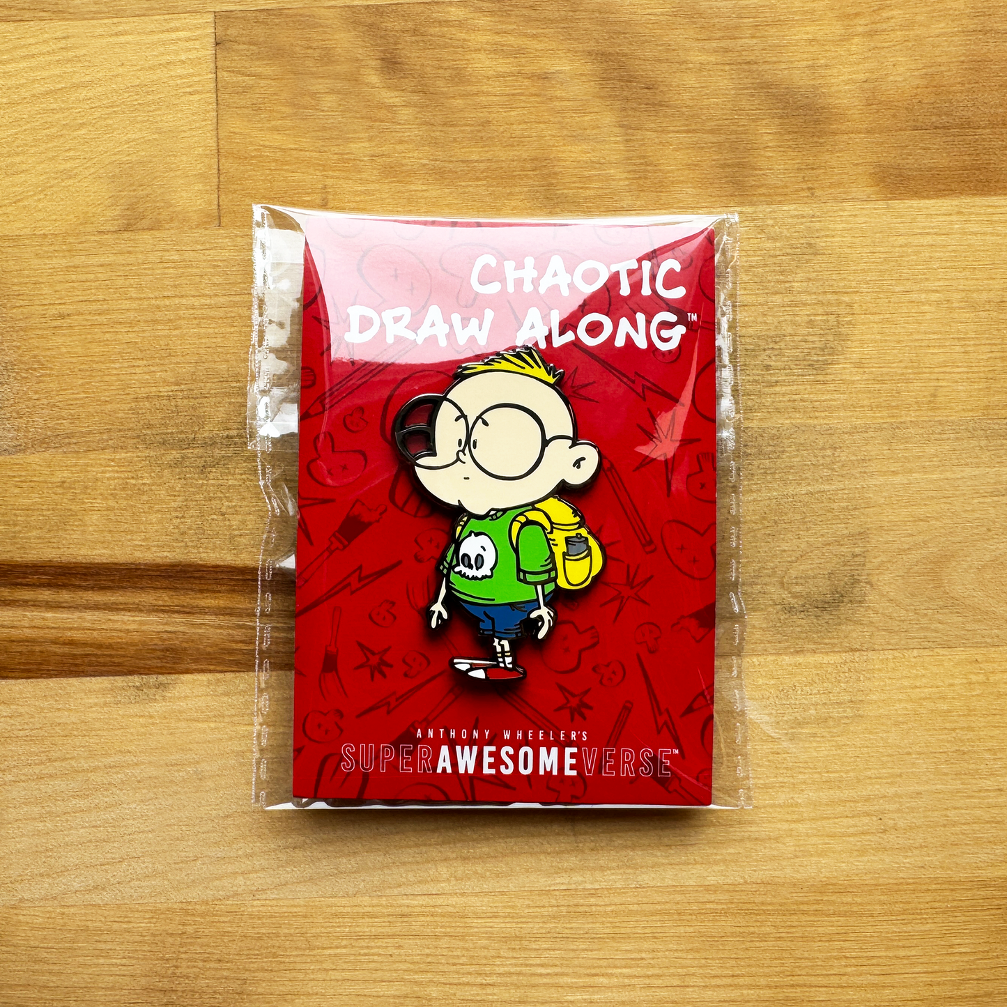 Chaotic Draw Along Gil enamel pin displayed on a red Super Awesomeverse backing card on a wooden tabletop.