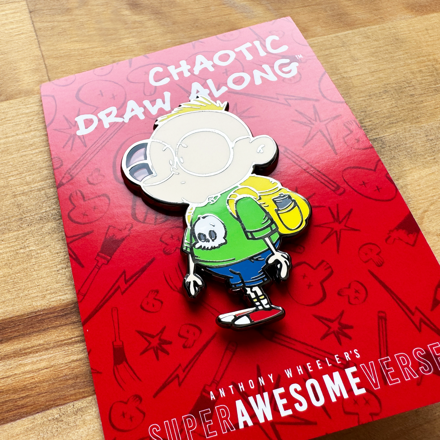 Chaotic Draw Along Gil enamel pin displayed on a red Super Awesomeverse backing card on a wooden tabletop.