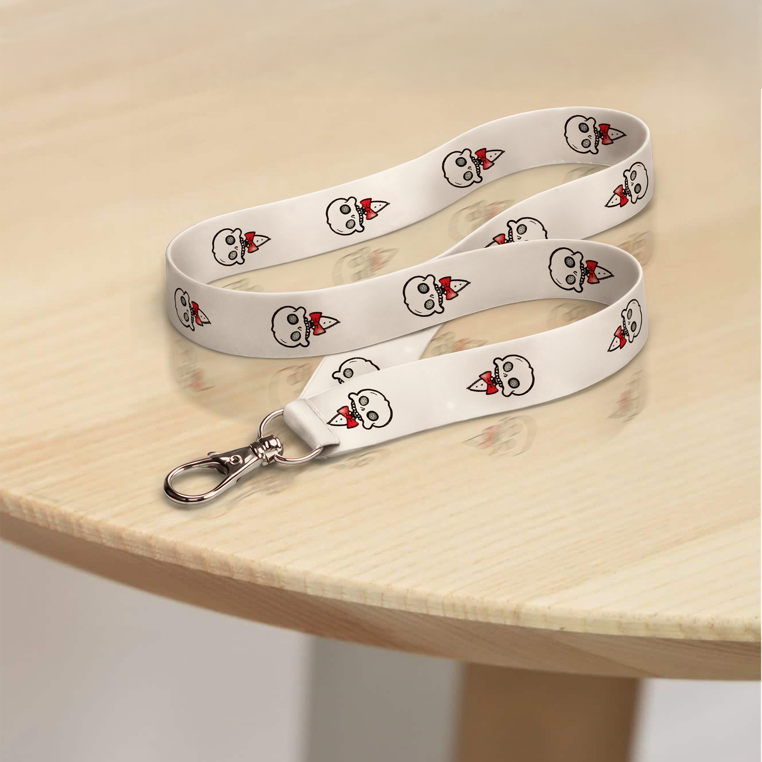Chaotic Draw Along white skull lanyard displayed on a light wooden table with repeating character artwork and metal clasp.
