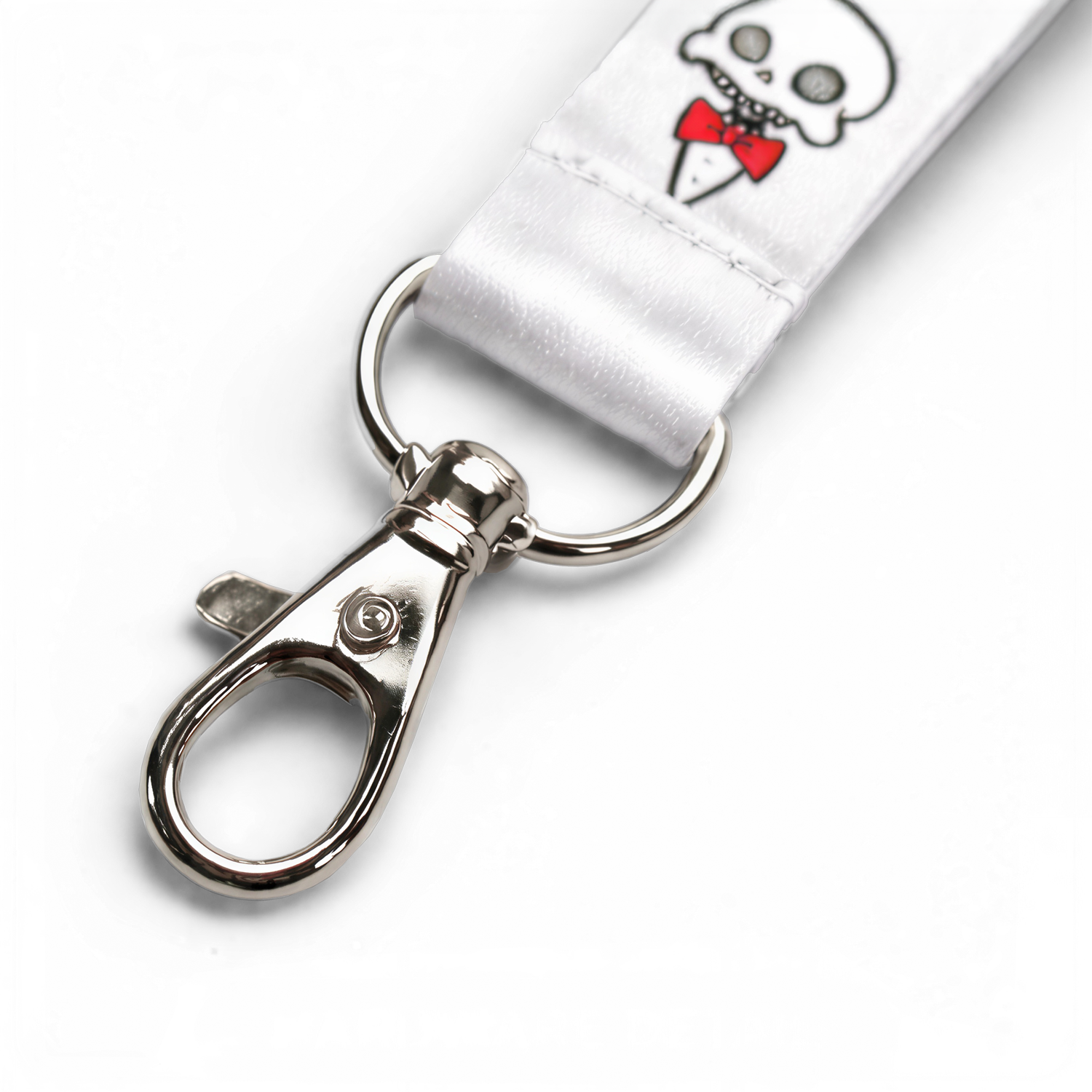Detail shot of the Chaotic Draw Along skull lanyard with white fabric, printed artwork, stitching, ring, and metal clasp.