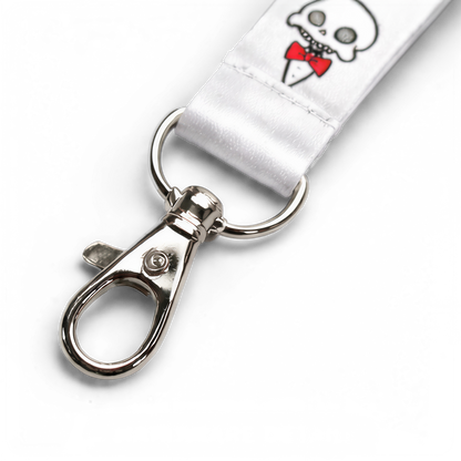Detail shot of the Chaotic Draw Along skull lanyard with white fabric, printed artwork, stitching, ring, and metal clasp.