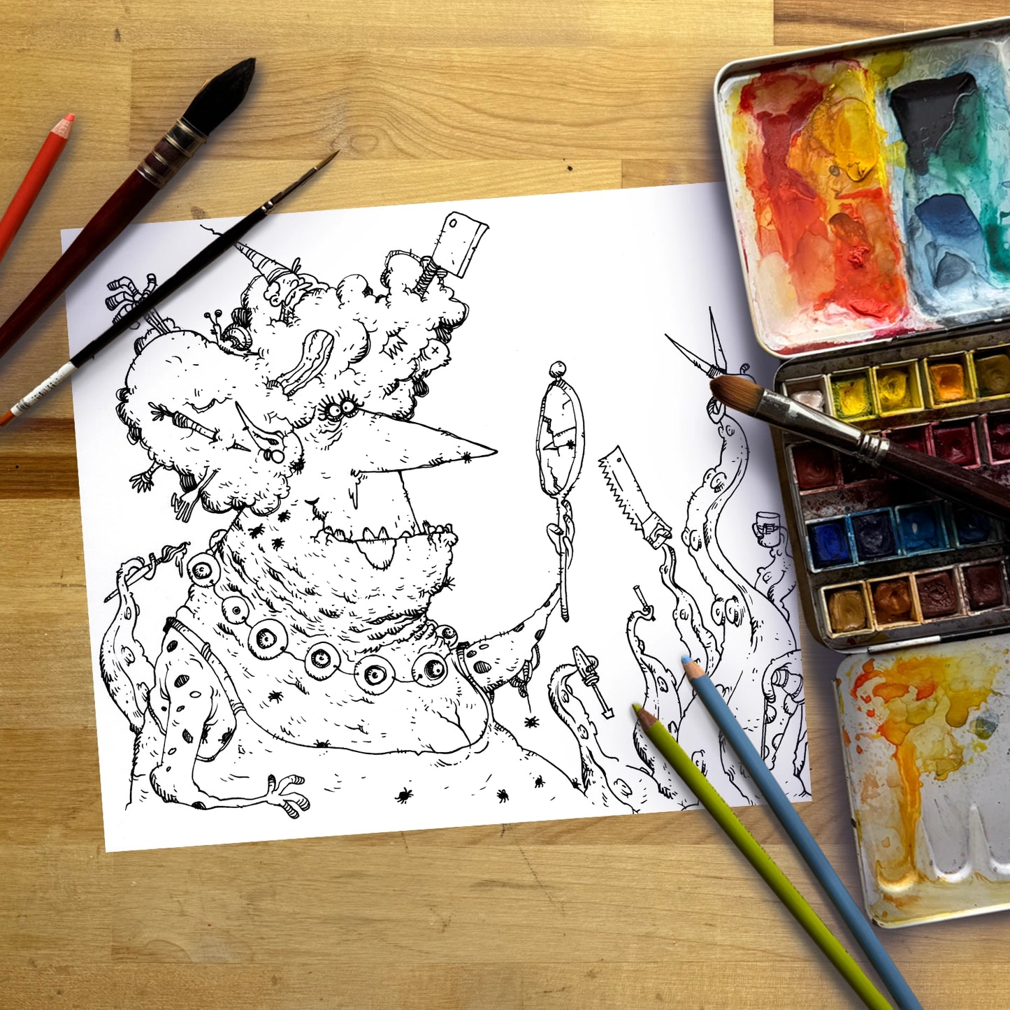 A black-and-white sketch of a whimsical, monstrous character on a sheet of white paper, arranged on a wooden surface with paintbrushes, a watercolor palette, and colored pencils.