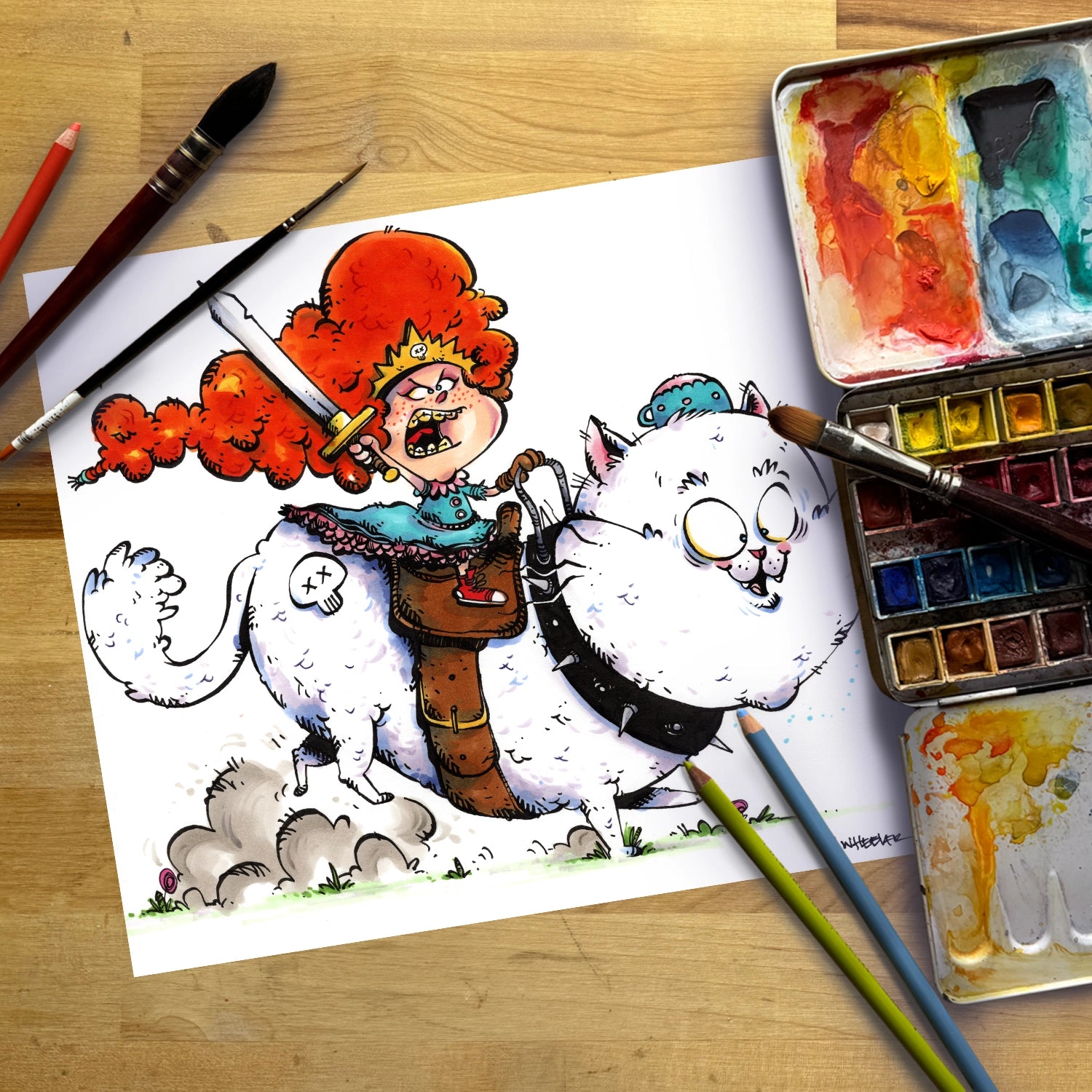 A cartoon-style illustration on a white sheet of paper showing a red-haired figure riding a white cat, surrounded by paintbrushes, watercolor paints, and a watercolor palette on a wooden surface.