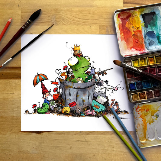 A whimsical cartoon illustration on a sheet of white paper, showing a green frog-like character sitting in a trash can with a small gnome and colorful trash elements. The paper is photographed from above on a wooden table with paintbrushes, a watercolor palette, and two paint sticks around it.