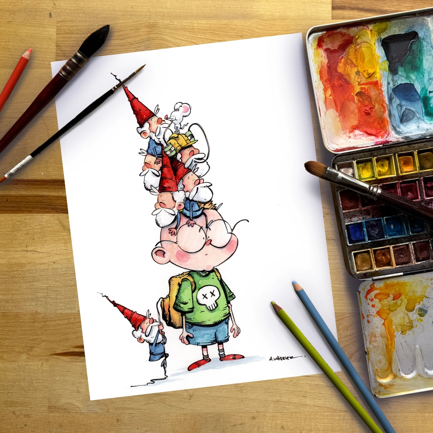 A cartoon drawing of two gnomes on a white sheet of paper, styled on a wooden table with watercolor paints, paintbrushes, and colored pencils.