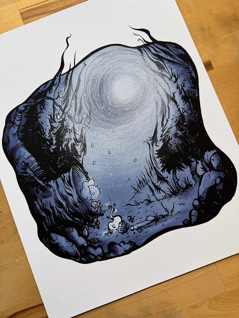 Lost in the Woods art print photographed at an angle showing forest scene and glowing light.