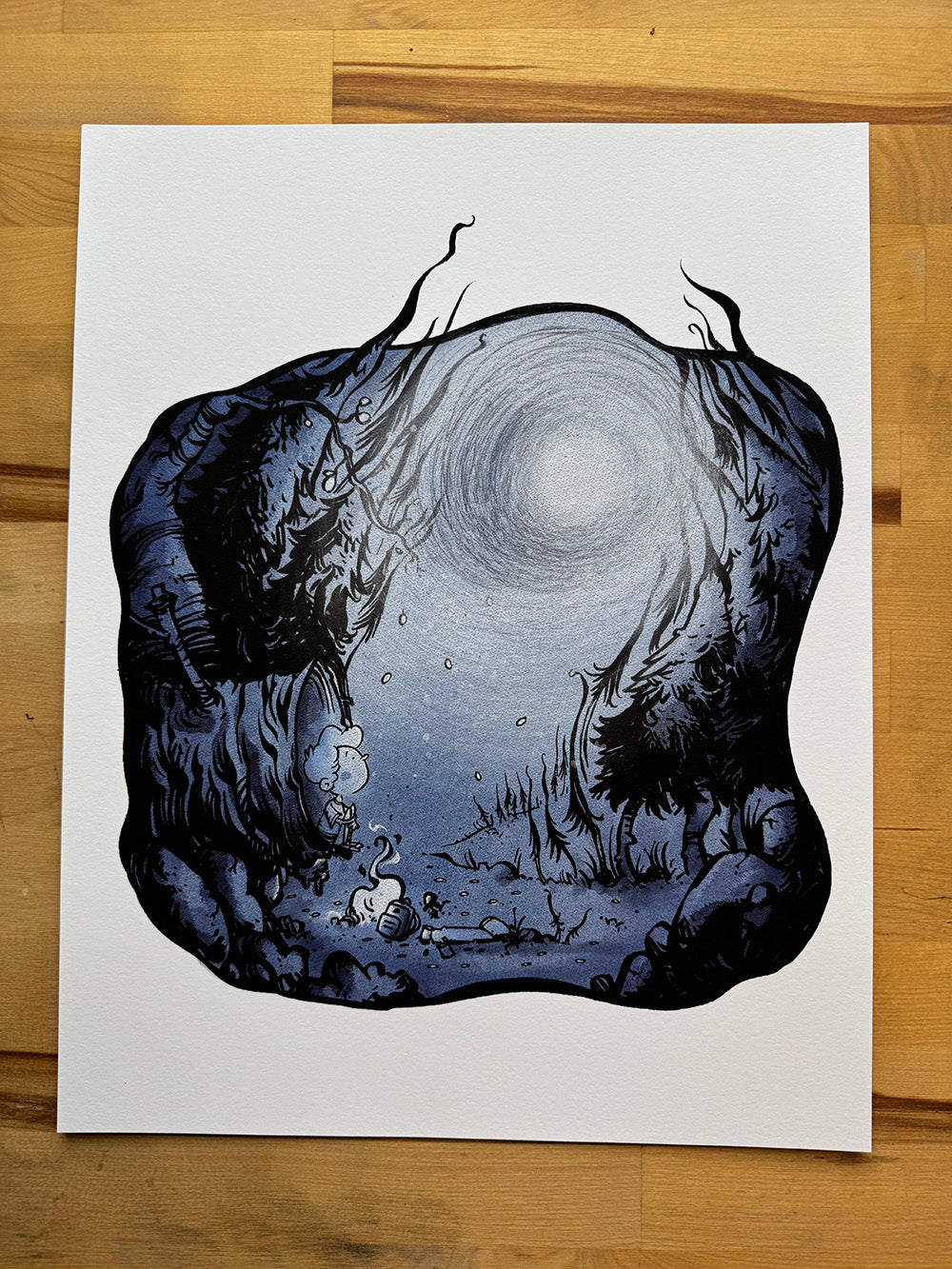 Lost in the Woods monochrome forest illustration art print by Anthony Wheeler on wooden desk.